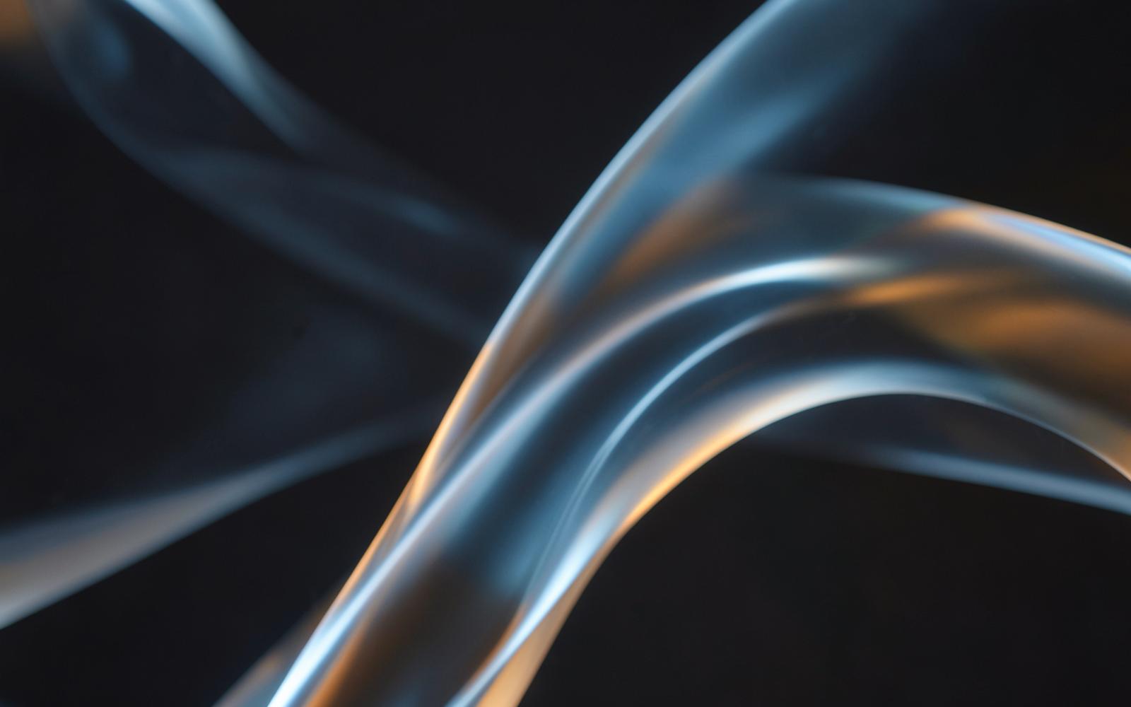 Flowing glass ribbons with blue and amber light representing connected creative technology